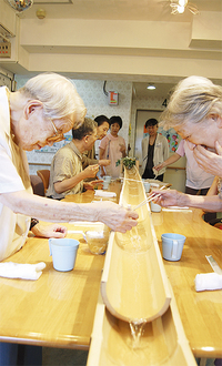 笑顔を見せ流しそうめんを楽しむ入居者たち