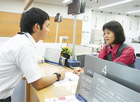 窓口で応対訓練をする行員（右）