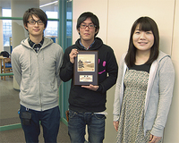 優勝盾に笑顔のメンバー（左から西村さん、藤倉ゼミ長、柴山さん）