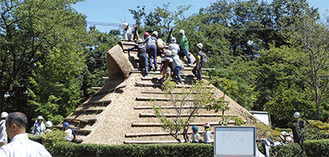 屋根に上り、最後の仕上げを行う参加者