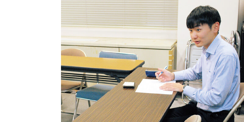 取材でメモをとる男性