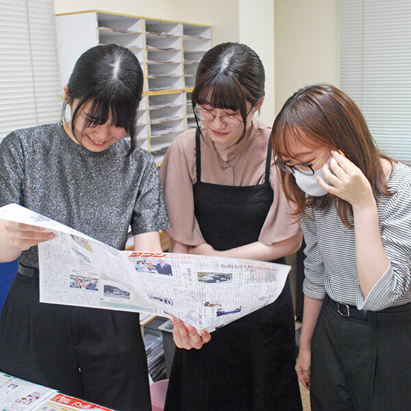 紙面に目を通す女性社員ら