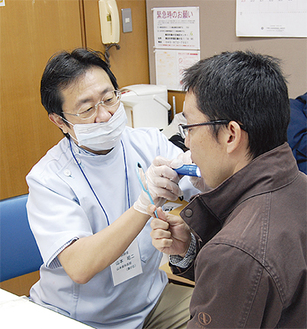 参加者の口腔内をチェックする歯科医師