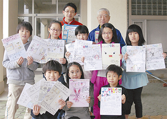 手づくりポスターを手にする児童ら。上段左は２組担任の北嶋晃吉（あきよし）教諭