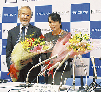 笑顔で会見に臨む大隅栄誉教授（左）と萬里子夫人