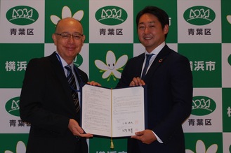 締結書を手にする小澤区長（左）と矢野代表