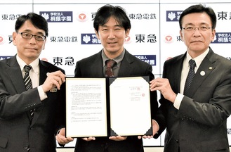 協定書を持つ（左から）東急の鈴置事業部長、溝上理事長、東急電鉄の福田社長