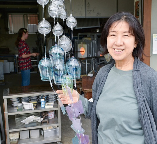 工房の前に立つ玉田さんと風鈴の試作品