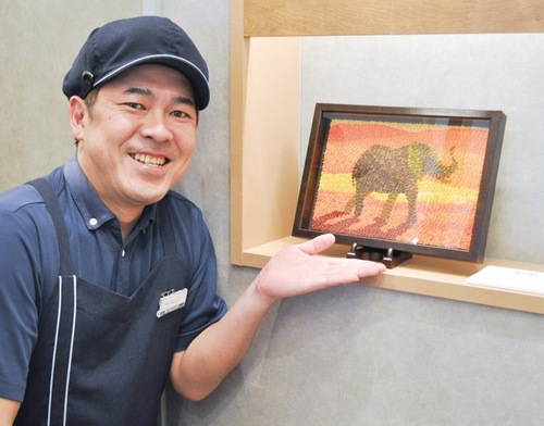 折り鶴を貼って描いた『お散歩』（中村崇浩さん作）と小菅店長