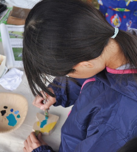 カワセミの飾りに色付けする少女