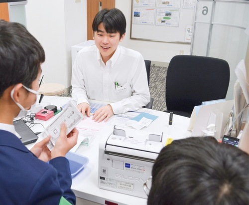 お金を預かり紙幣を数える生徒（左）