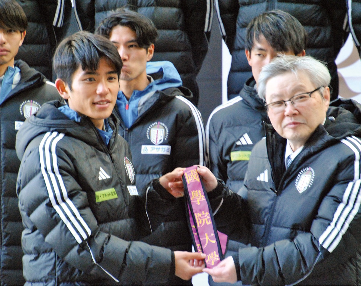 針本学長から“たすき”を受け取る上原主将