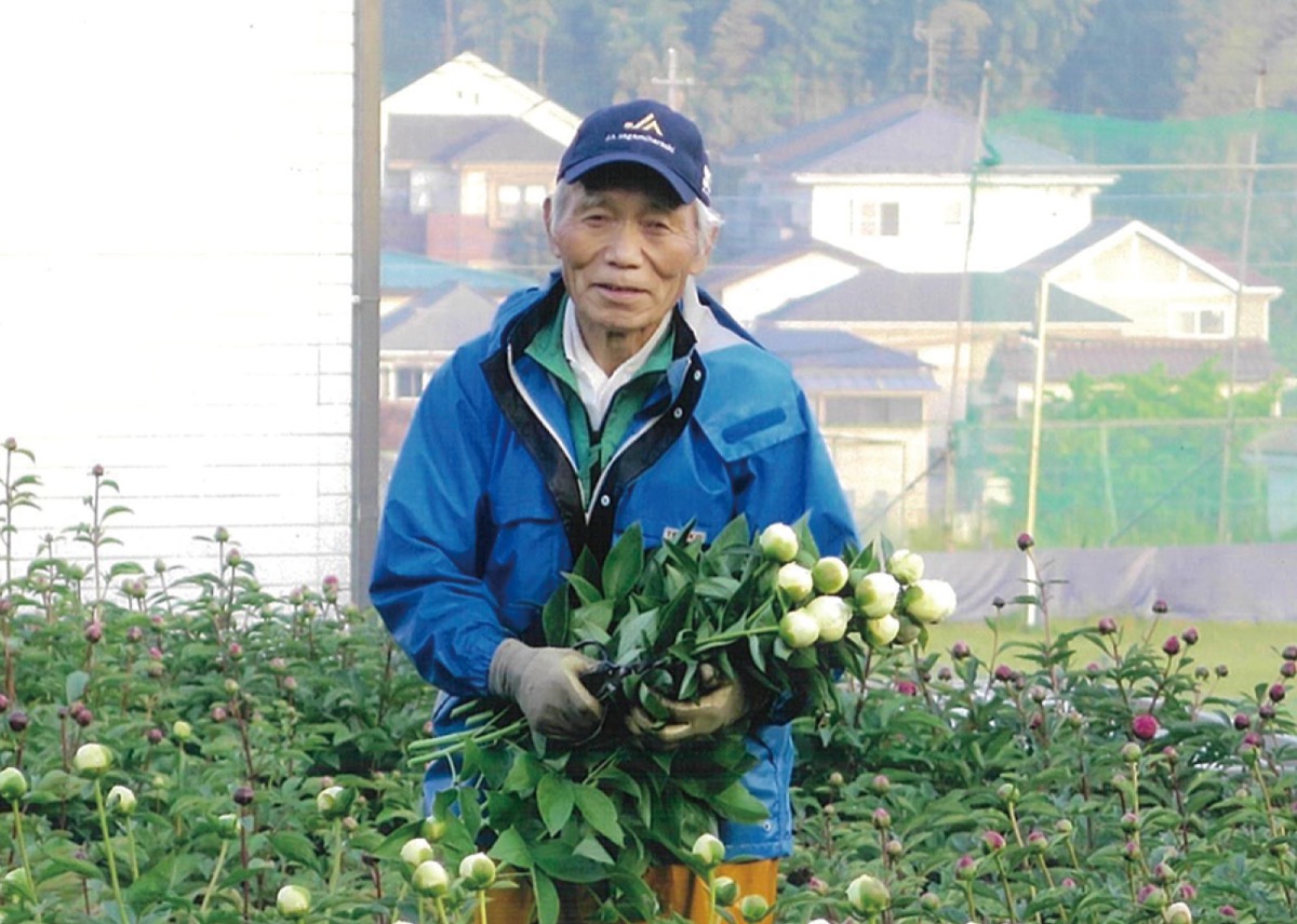 畑の真ん中でほほ笑む志村さん＝本人提供