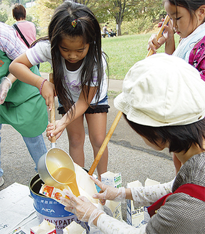 手作り石鹸のもとを牛乳パックに流し込む参加児童