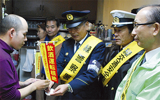 飲酒運転根絶旗を受け取る飲食店従業員（左）
