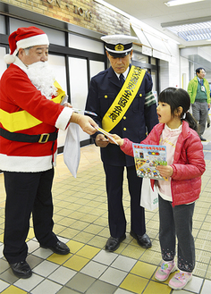 駅を利用した子どもに啓発チラシを配る津田区長（左）