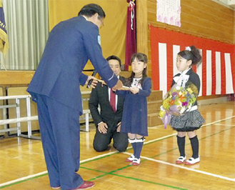 岩岡会長からカバーを受け取る児童