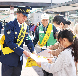 通行人にチラシを配る磯野緑警察署長（左）