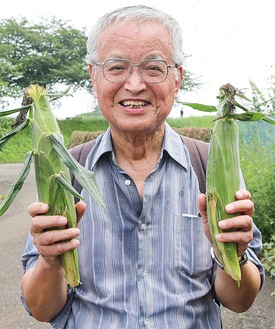 収穫したトウモロコシを手に笑顔の参加者