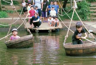 たらい船で池を横断する子どもたち（提供写真）