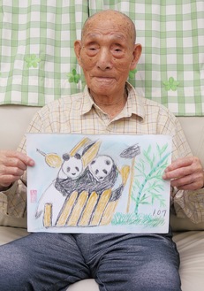 自身が描いたパンダの絵を持つ池田さん