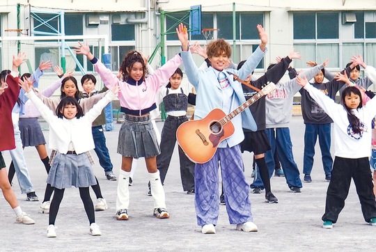 校庭で撮影を行ったおにちゃん（中央）と児童たち