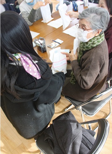 廃油を再利用して作った石けんを手渡す児童（左）