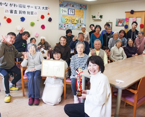 水車の里の職員と入居者たち。中央で表彰状を手にしているのが管理者の高田さん