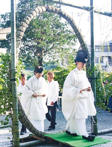 大きな茅の輪をくぐる小野宮司（右）