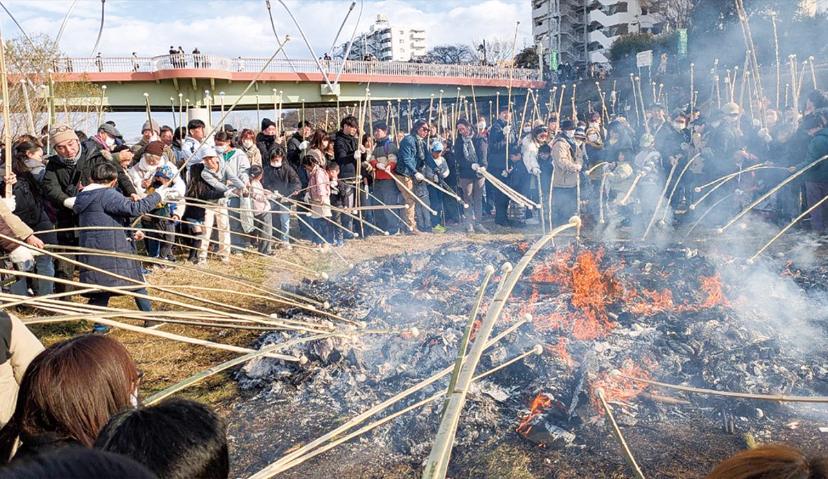 火に向かって竹串を伸ばす大勢の来場者（鴨居連合自治会提供）
