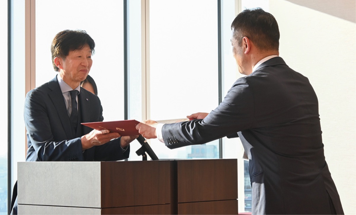 表彰式で賞状を受け取る中村教諭（右。鴨居中学校提供）