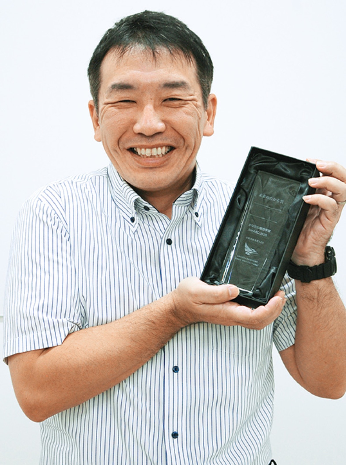 受賞トロフィーを持つ長島教諭
