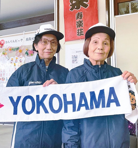 市のタオルを掲げる(左から)杉山さんと猪俣さん