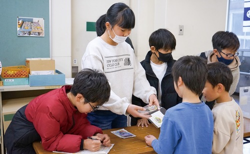 １年生に缶バッジを手渡す６年生ら
