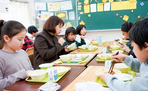 山崎校長（中央）と喫食する児童ら