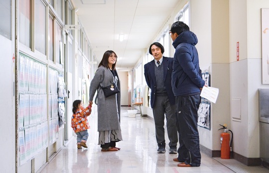 館校長と思い出話をする卒業生とその家族