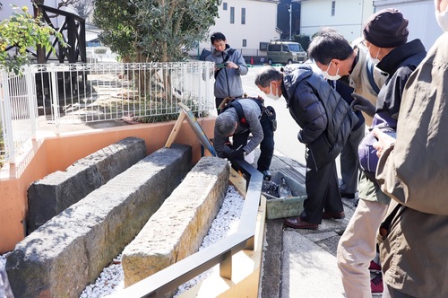 ▲案内板の設置を見守る地域の関係者ら