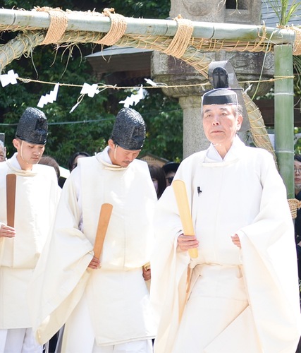茅の輪をくぐる石川宮司（右）と神職