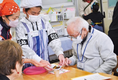 来場者に大学芋を運ぶ児童