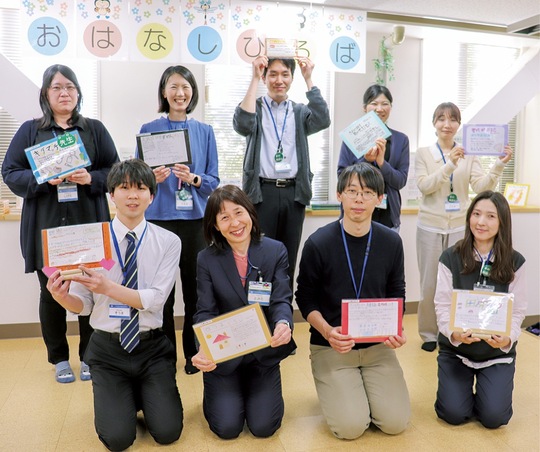 児童たちが作ったポップを手にする冨田館長(前列左から2人目）と職員ら