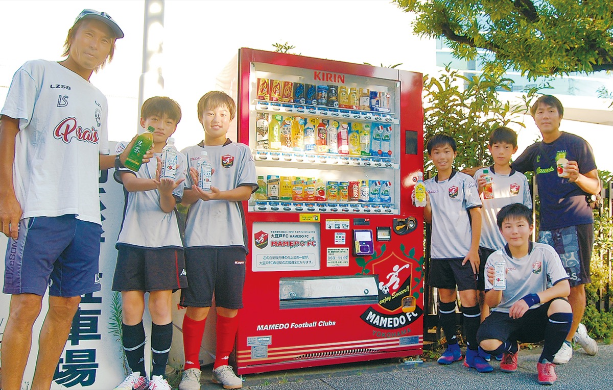 自販機を囲むクラブ指導者と選手たち（一番左が末本代表理事）