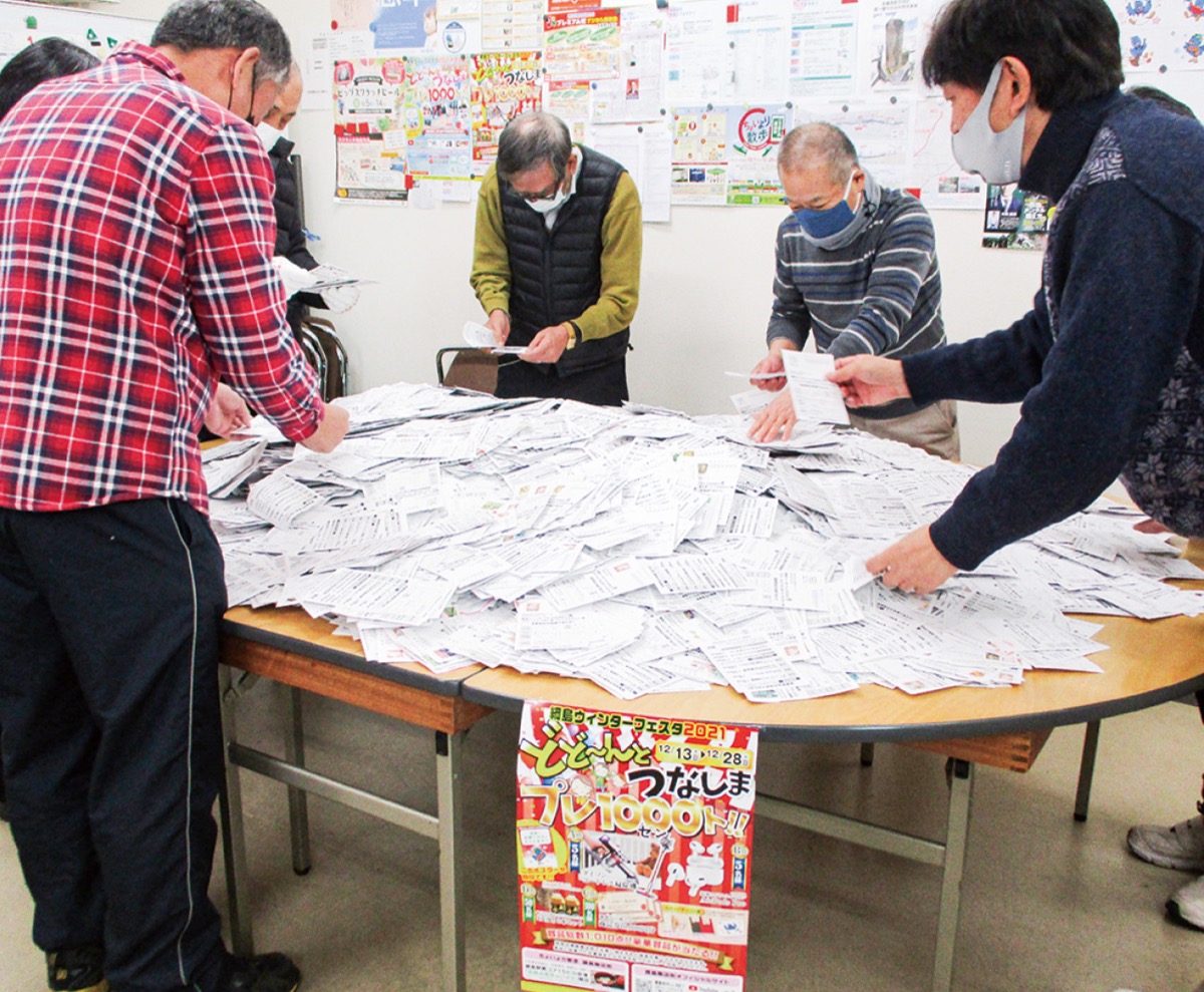 ハガキを前に作業する同会=提供