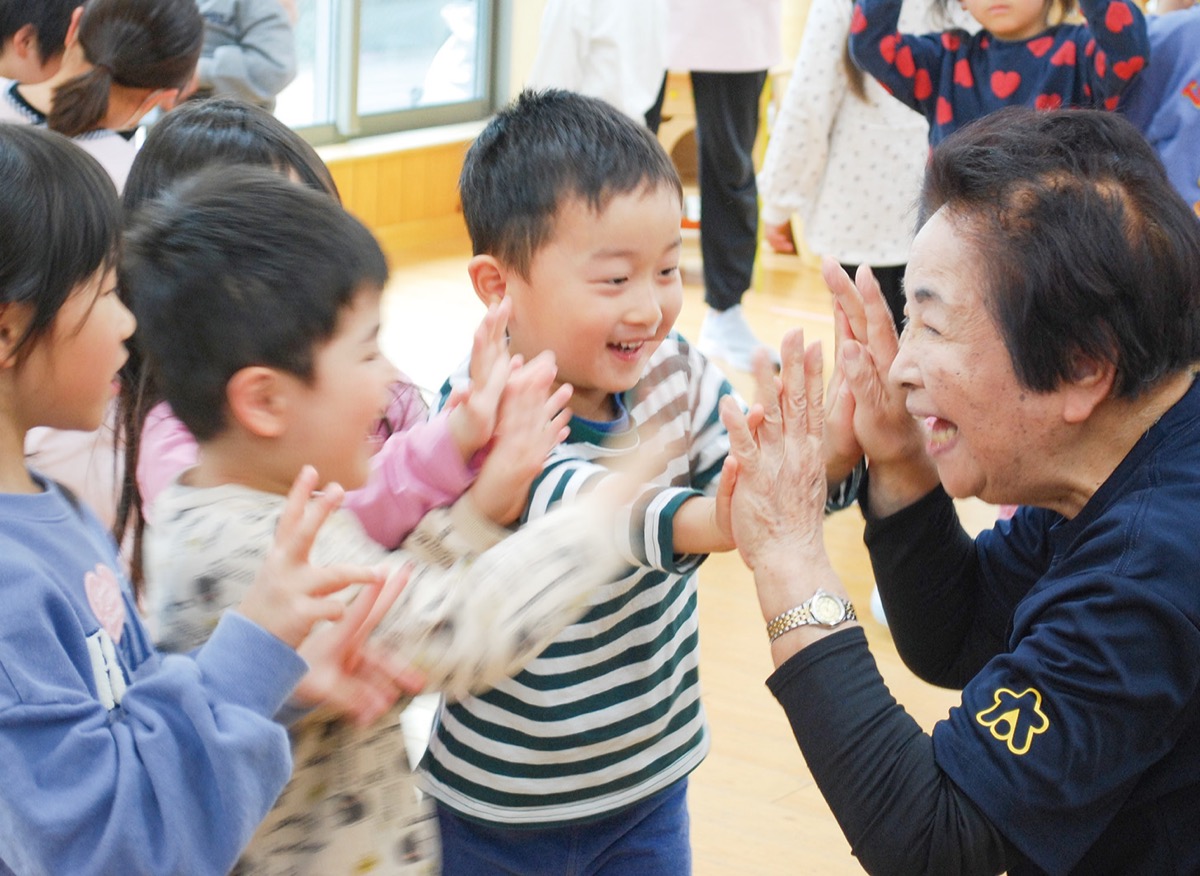 ハイタッチする久米川さんと園児