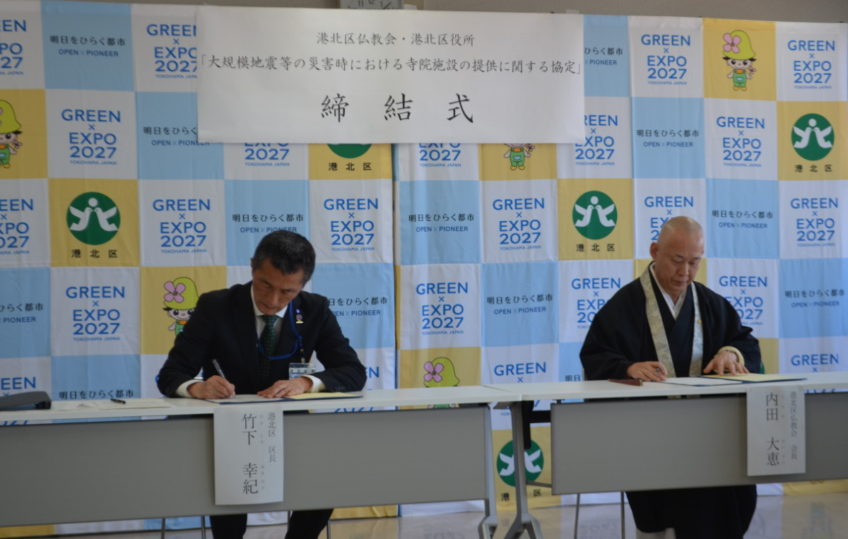 協定書にサインをする竹下区長（左）と内田住職