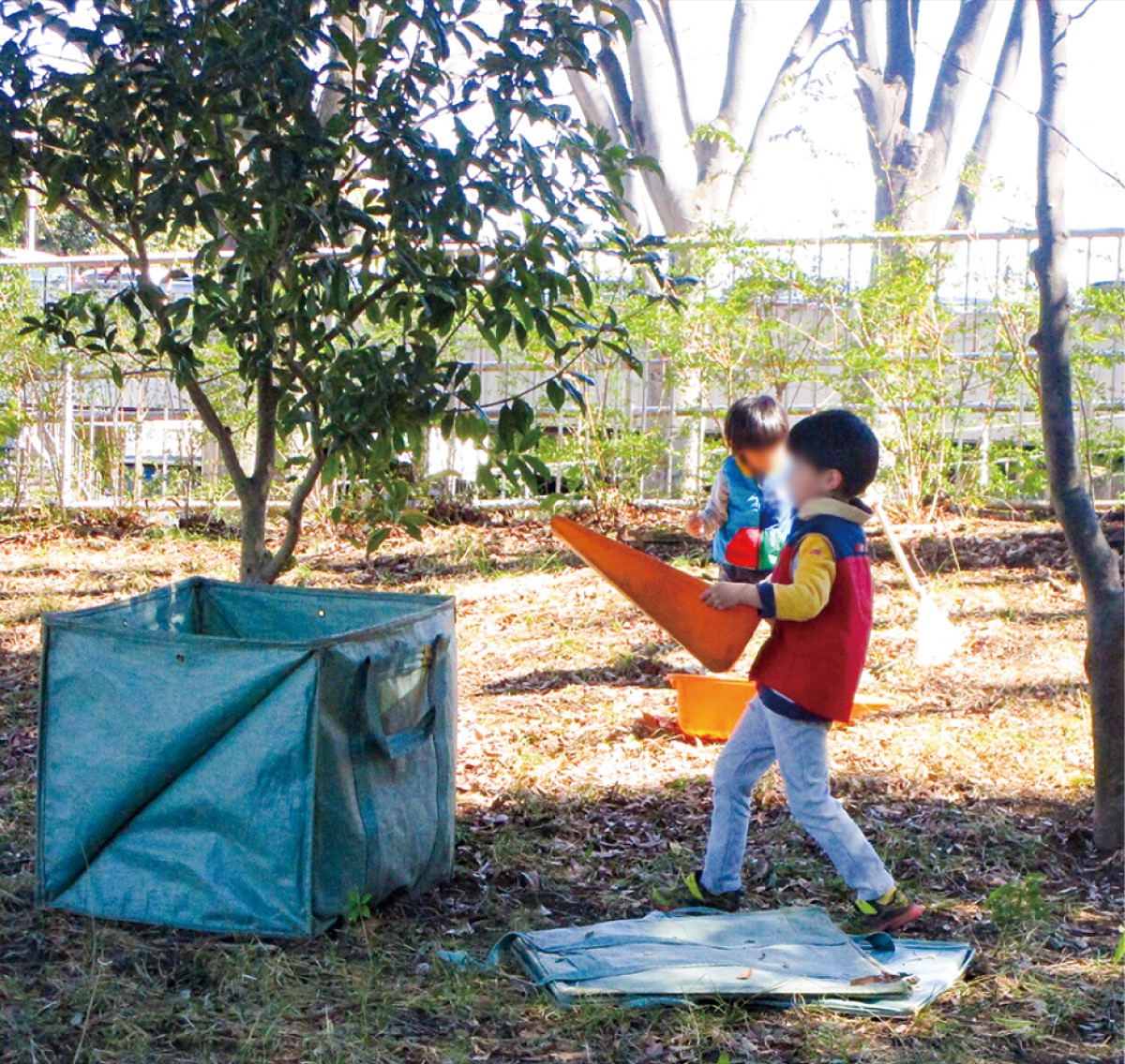 重い枯葉を運ぶ子ども