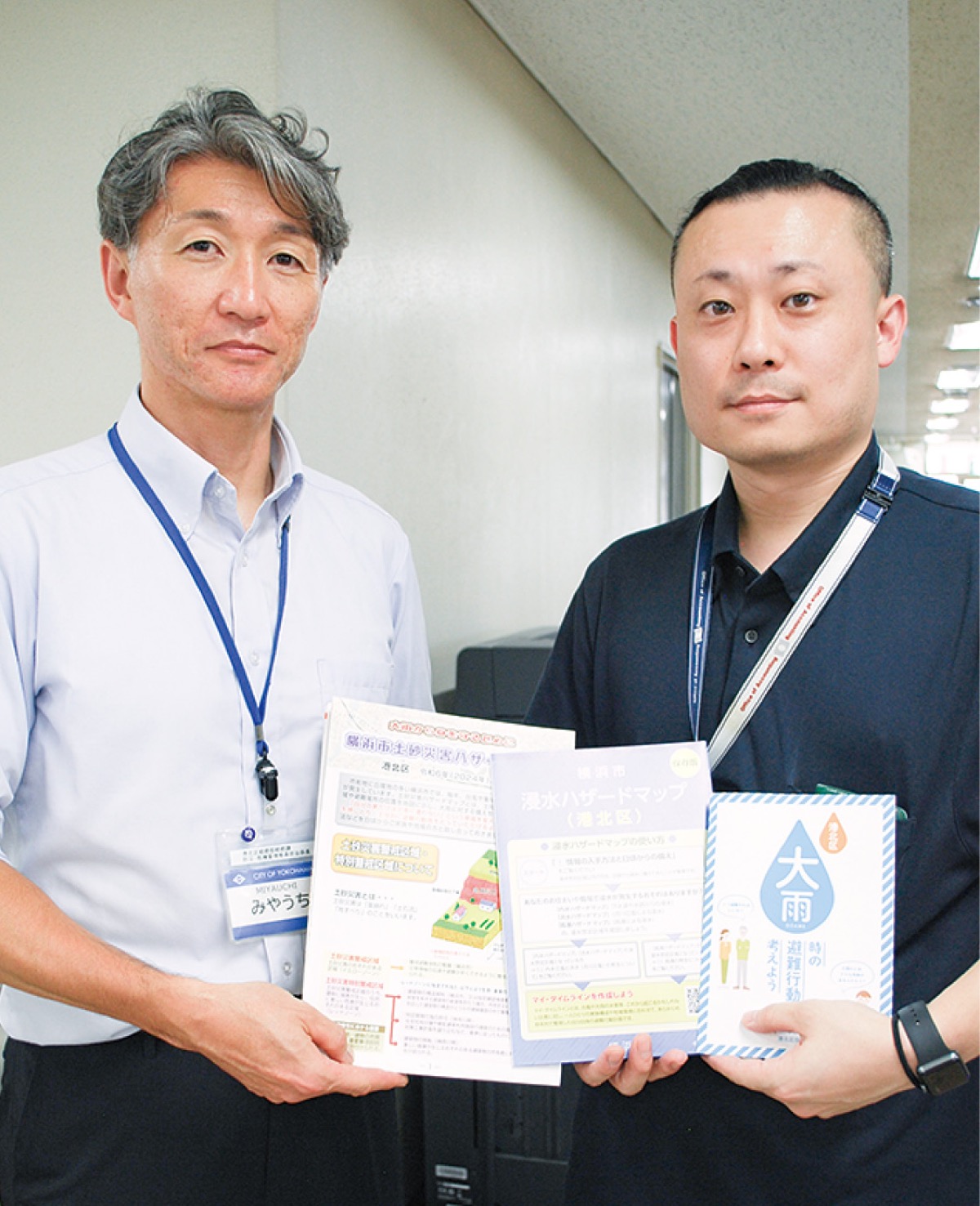 ハザードマップや啓発冊子を手にする区職員