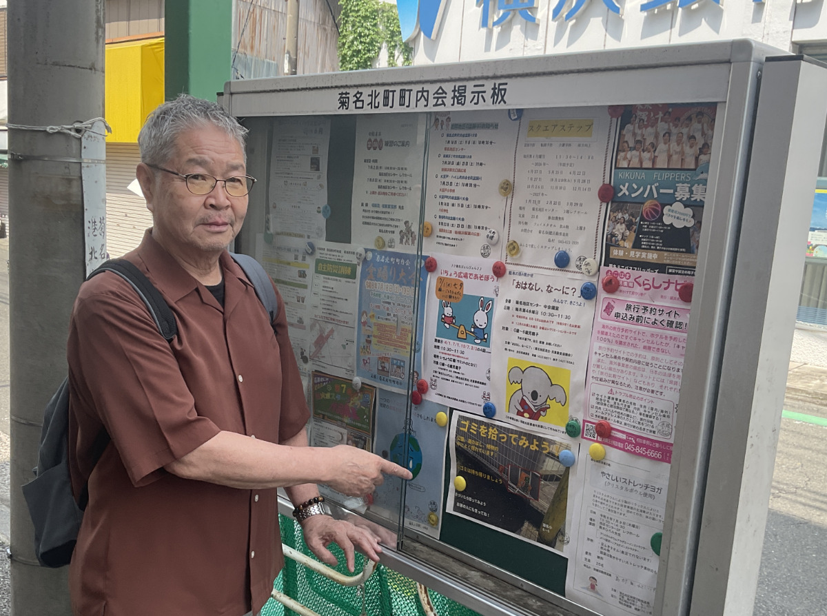 菊名小の児童が制作したポスターを指さす長井会長