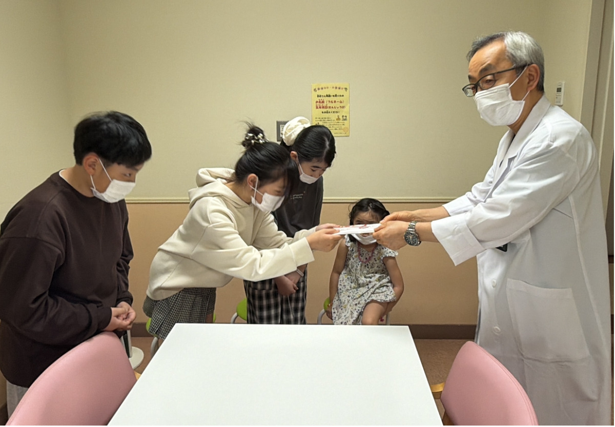 後藤医師（右）に寄付金を手渡す子どもたち