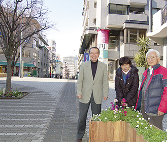 中央遊歩道の花壇ベンチ前に立つプロジェクトメンバー