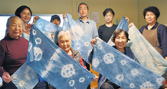 つづきブルーに染まった作品を手にする参加者と柏崎代表（後列右から２番目）